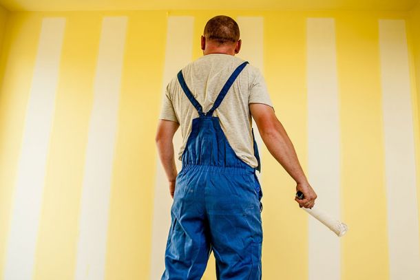 Photo d'un homme en train de peintre un mur